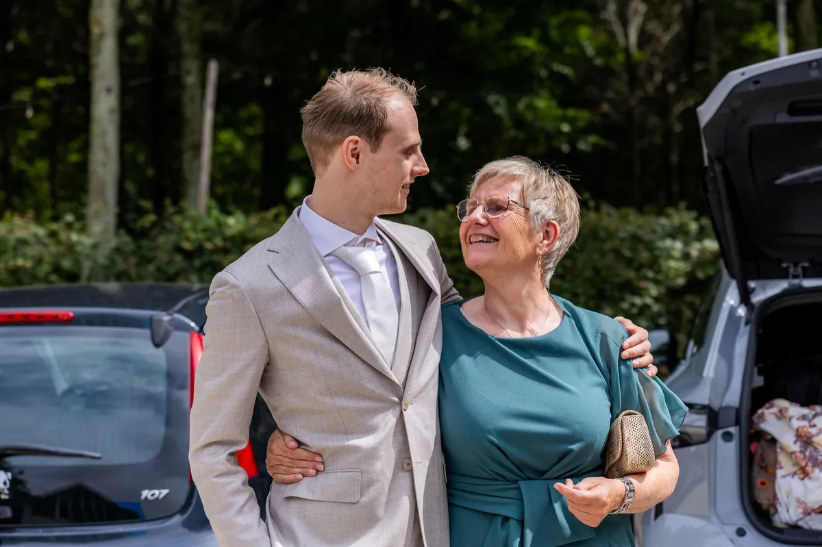 De bruidegom en zijn moeder lachen naar elkaar op de trouwdag