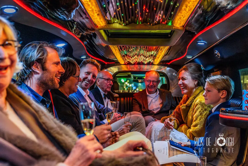 Gasten proosten met champagne in een limousine met gekleurde lichtjes