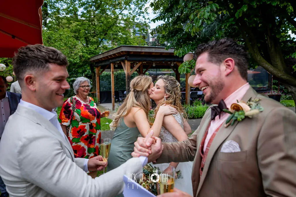 De bruidegom wordt gefeliciteerd met een stevige handdruk in de tuin van Kloosterhotel Soete Moeder
