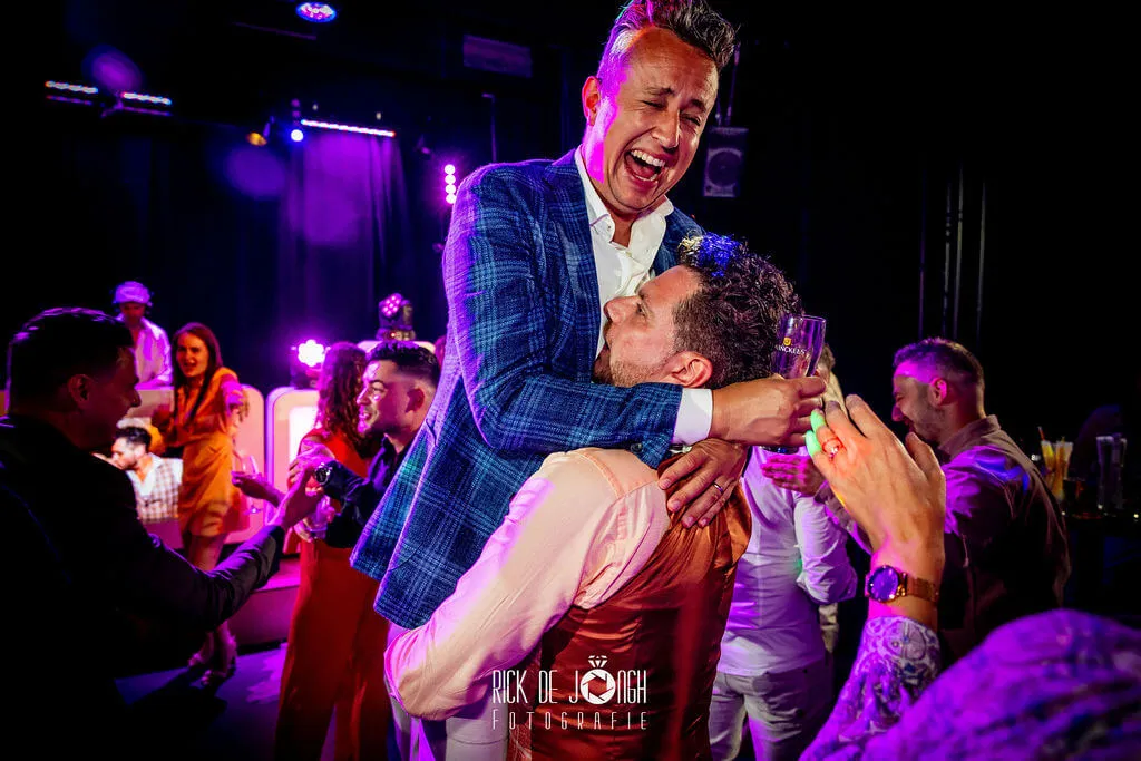 Een vriend tilt de lachende bruidegom op op de dansvloer