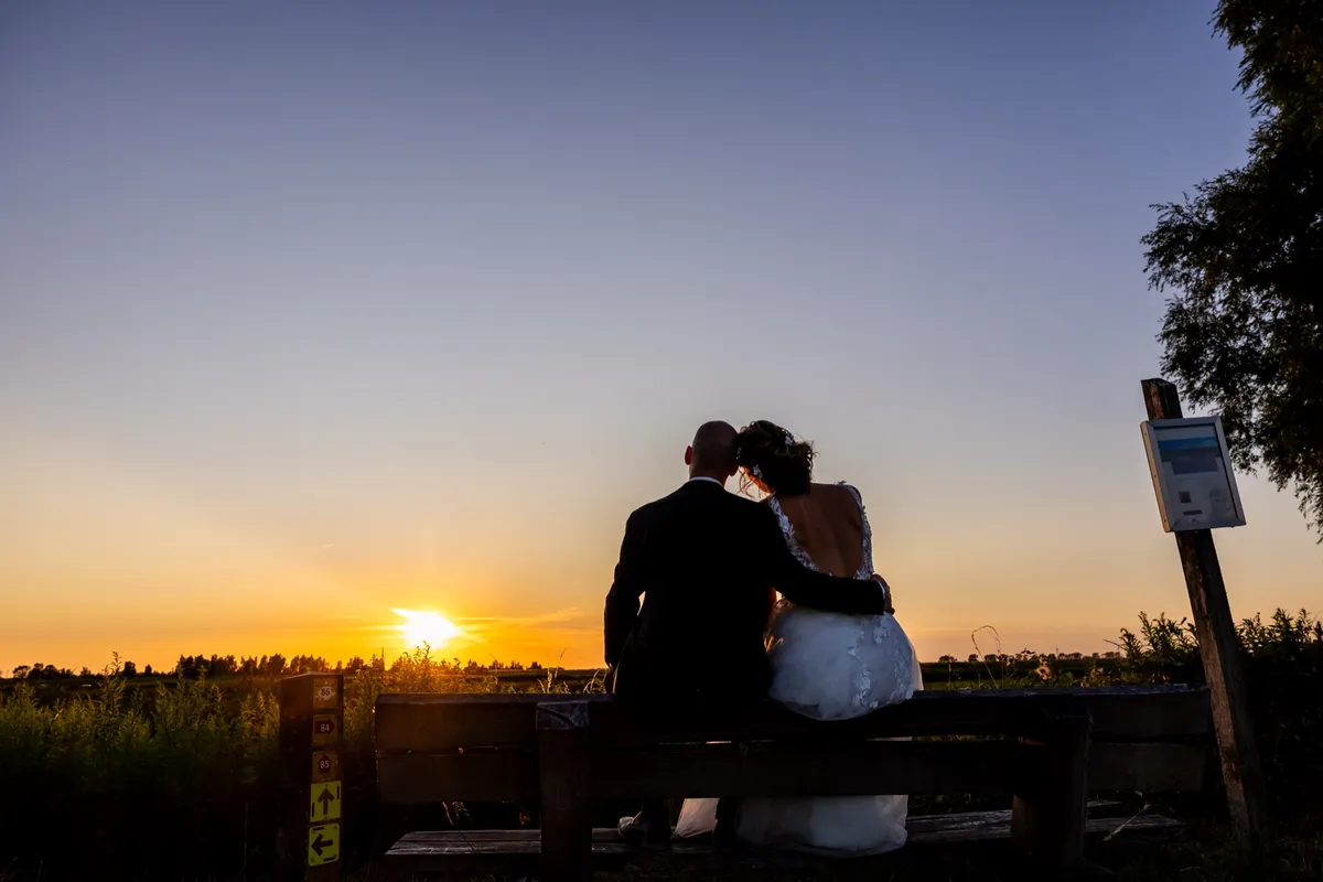 Silhouet van het bruidspaar op een bankje bij zonsondergang op Tiengemeten