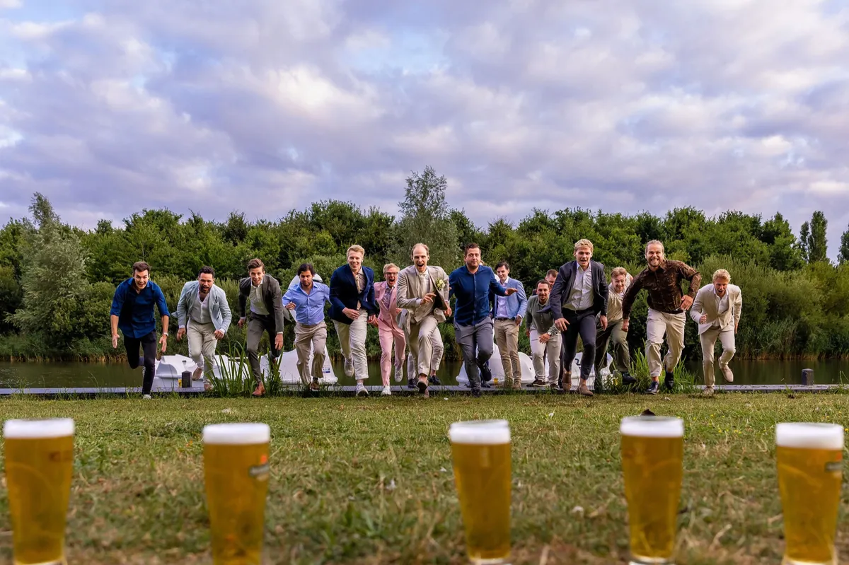 Vrienden rennen naar de biertjes op het gras, met de glazen op de voorgrond