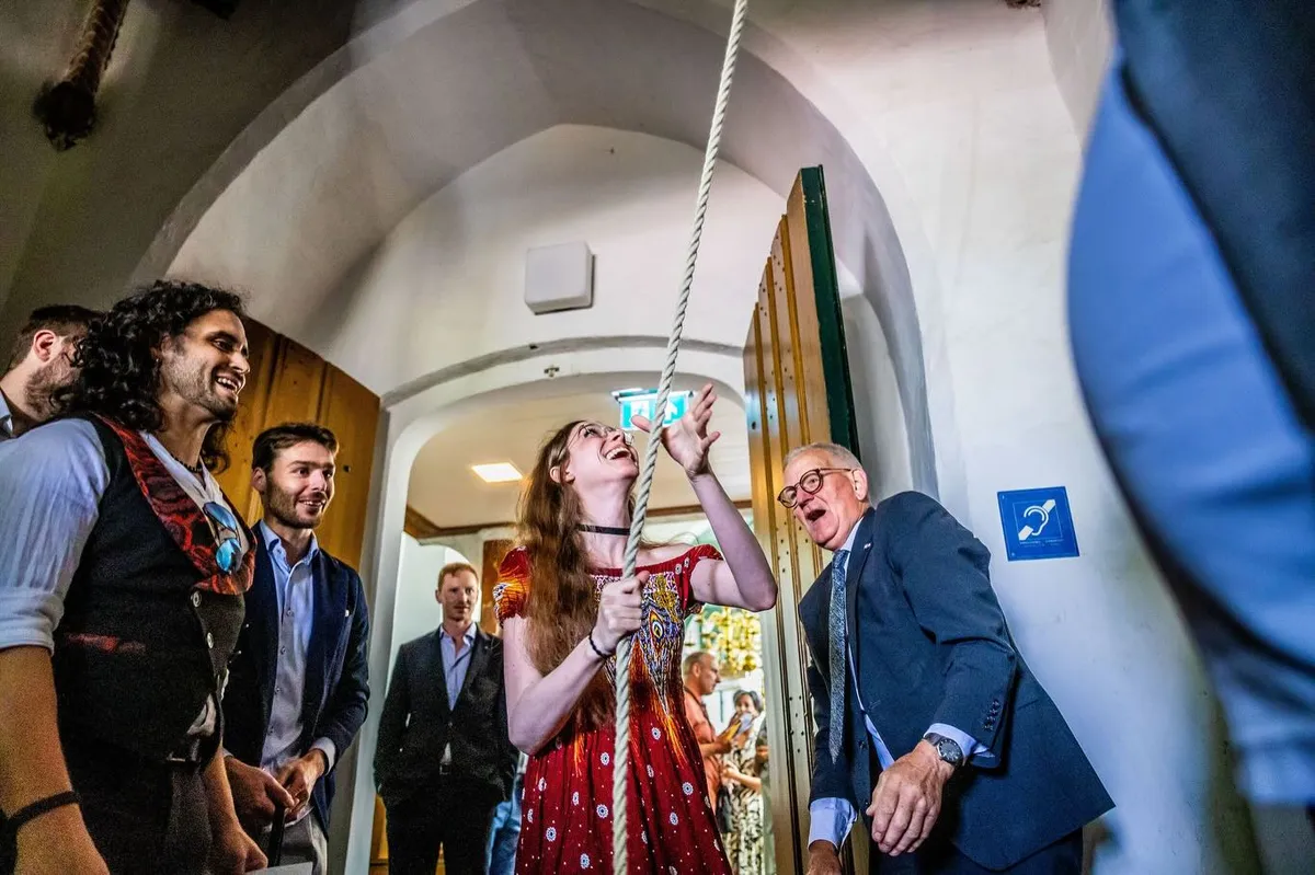 Een gast luidt de kerkklok van het oude kerkje in Kortenhoef, de anderen kijken lachend toe