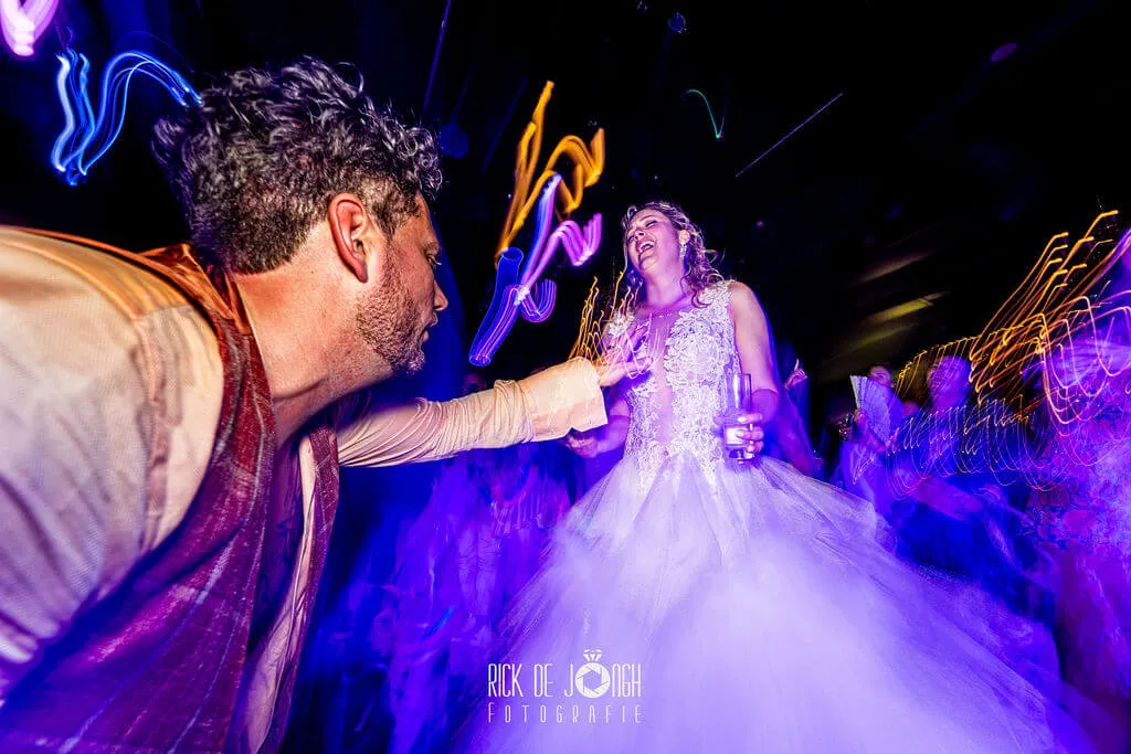 Het bruidspaar danst tussen paarse lichtsporen op het feest