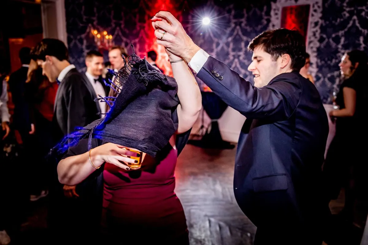 Gasten dansen uitgelaten op het feest onder het rode en paarse licht