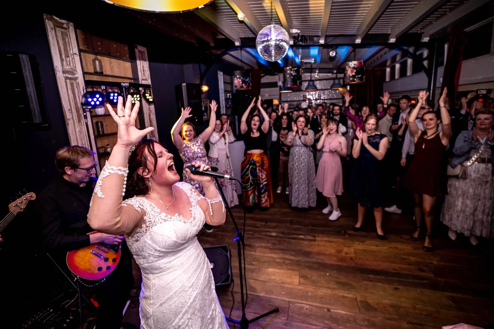 De bruid zingt uit volle borst met de band terwijl de gasten juichen
