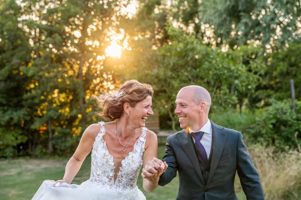 Het bruidspaar loopt hand in hand in het gouden licht van de ondergaande zon