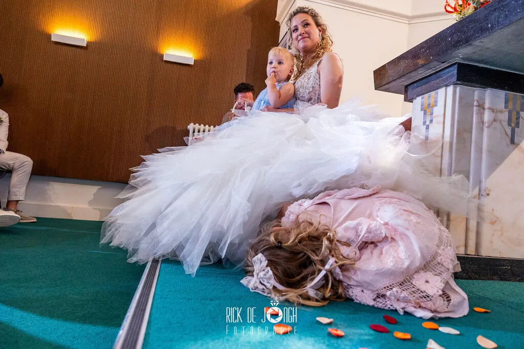 Tijdens de ceremonie zit de bruid met een peuter op schoot, een meisje ligt languit op de vloer