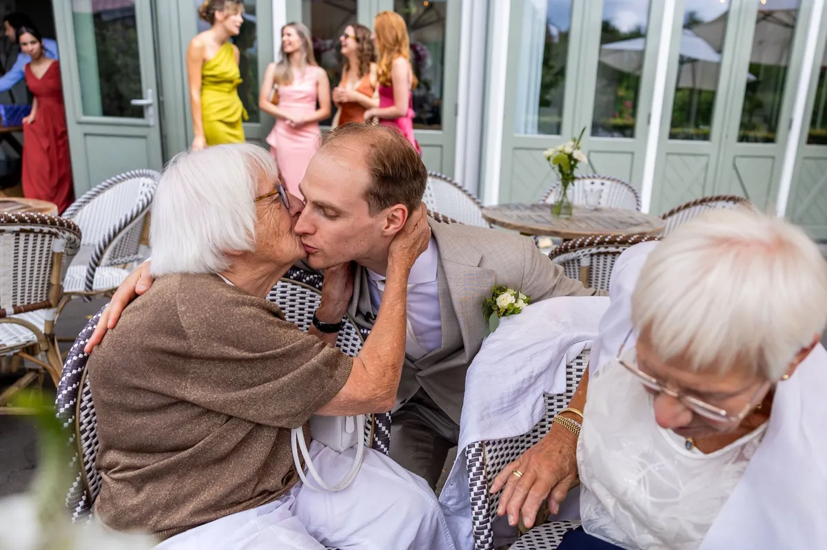 Oma geeft de bruidegom een kus vlak voor de ceremonie