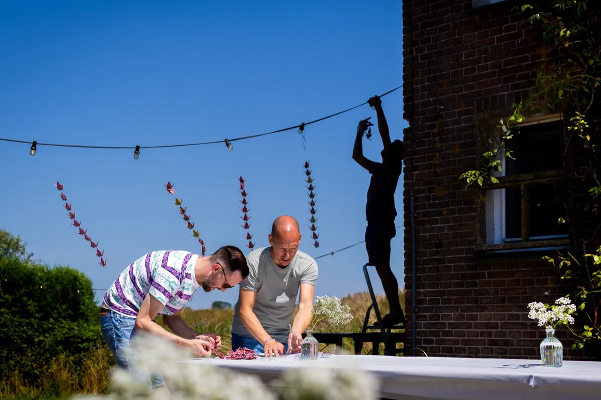 Gasten hangen slingers met zelfgevouwen origami kraanvogels op bij Tiny Parks Tiengemeten