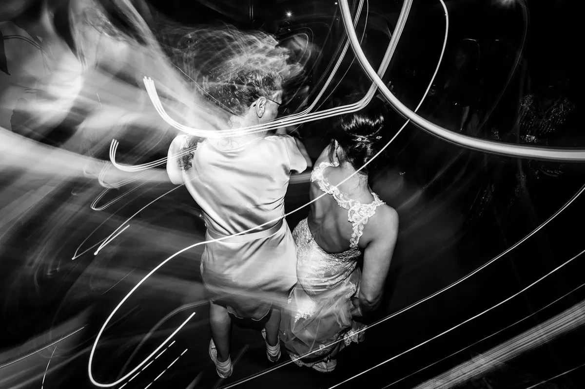 De bruid danst met een vriendin tussen lichtstrepen op het feest (zwart-wit)