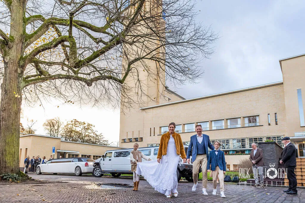 Het bruidspaar loopt met de kinderen langs de limousines voor het raadhuis van Hilversum