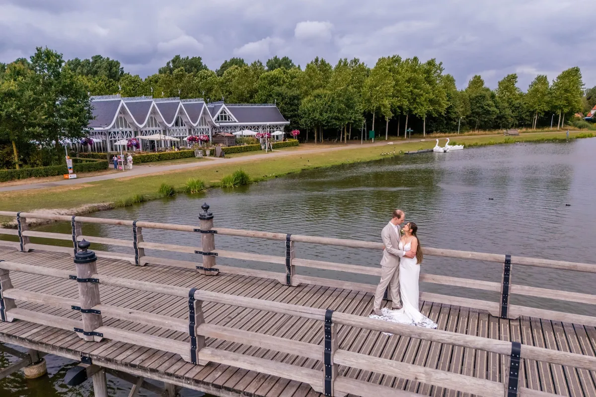 Dronefoto van het bruidspaar op de steiger bij Anafora Utrecht, met het water en de trouwlocatie op de achtergrond