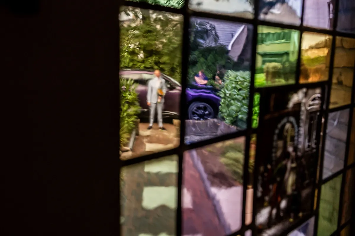 Door het glas-in-lood van het huis is de bruidegom te zien die buiten wacht op zijn bruid