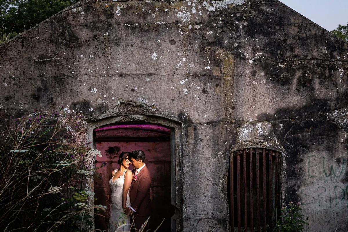 Het bruidspaar in een verlichte deuropening van een oude bunker van Fort Diemerdam