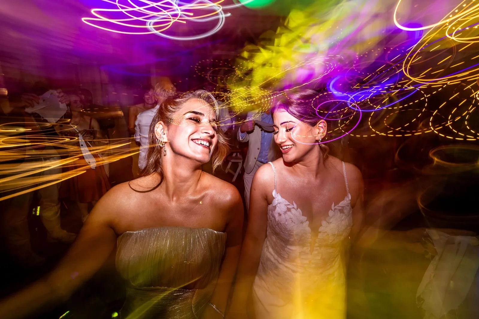 De bruid en haar zus dansen op het feest tussen kleurrijke discolichten