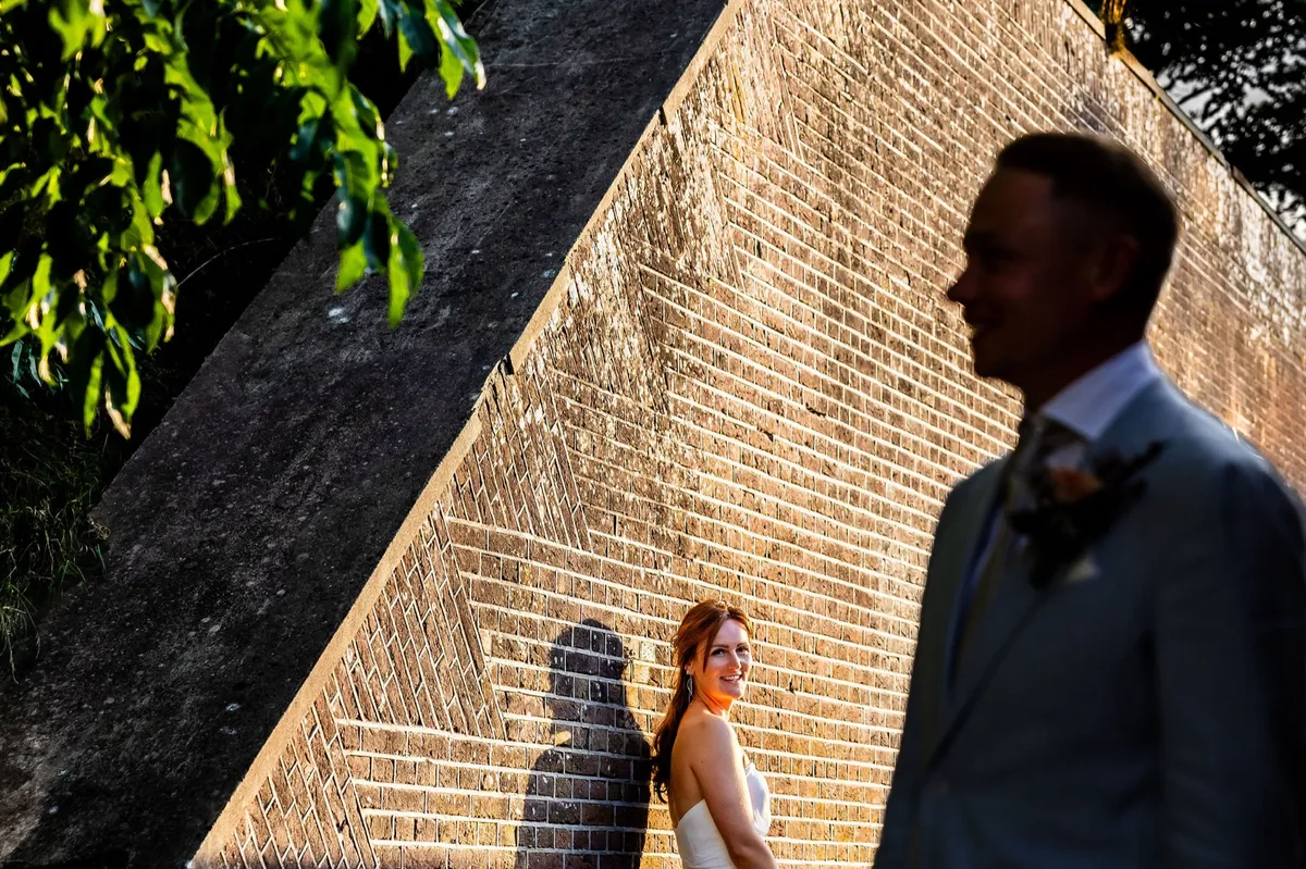 Silhouet van de bruid en bruidegom tegen de zonovergoten bakstenen muur van het fort