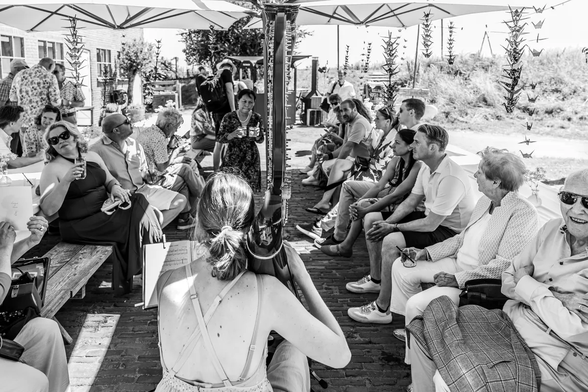 Gasten wachten op het terras op de ceremonie (zwart-wit)