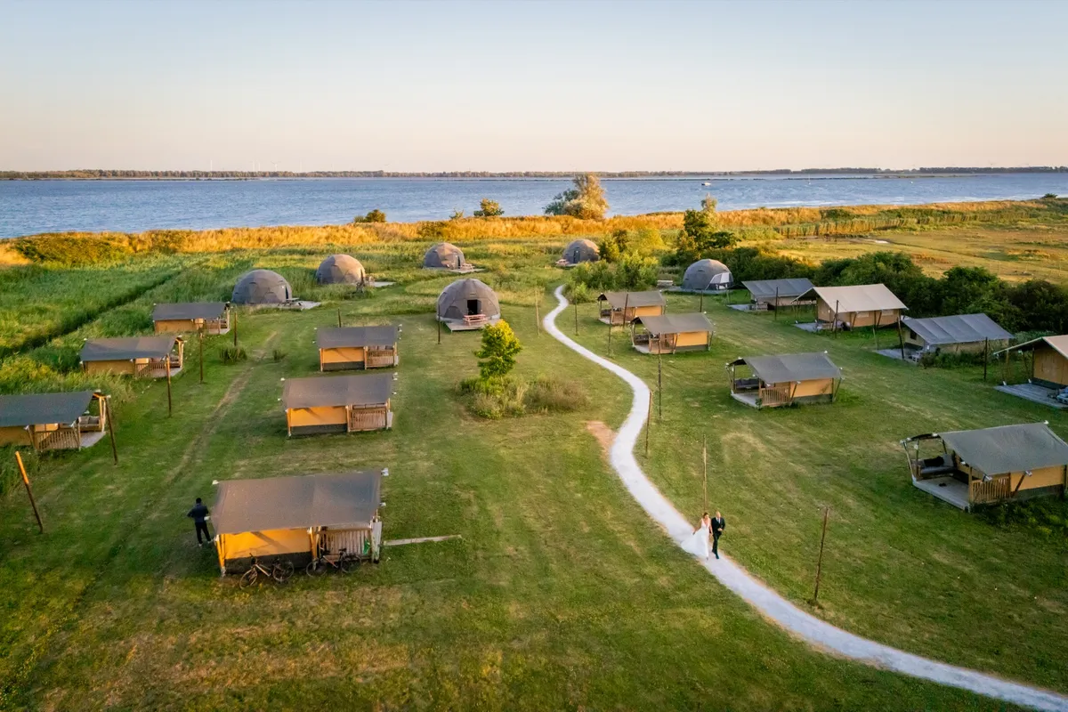 Dronefoto van Tiny Parks op het eiland Tiengemeten, met de huisjes en het water van het Haringvliet