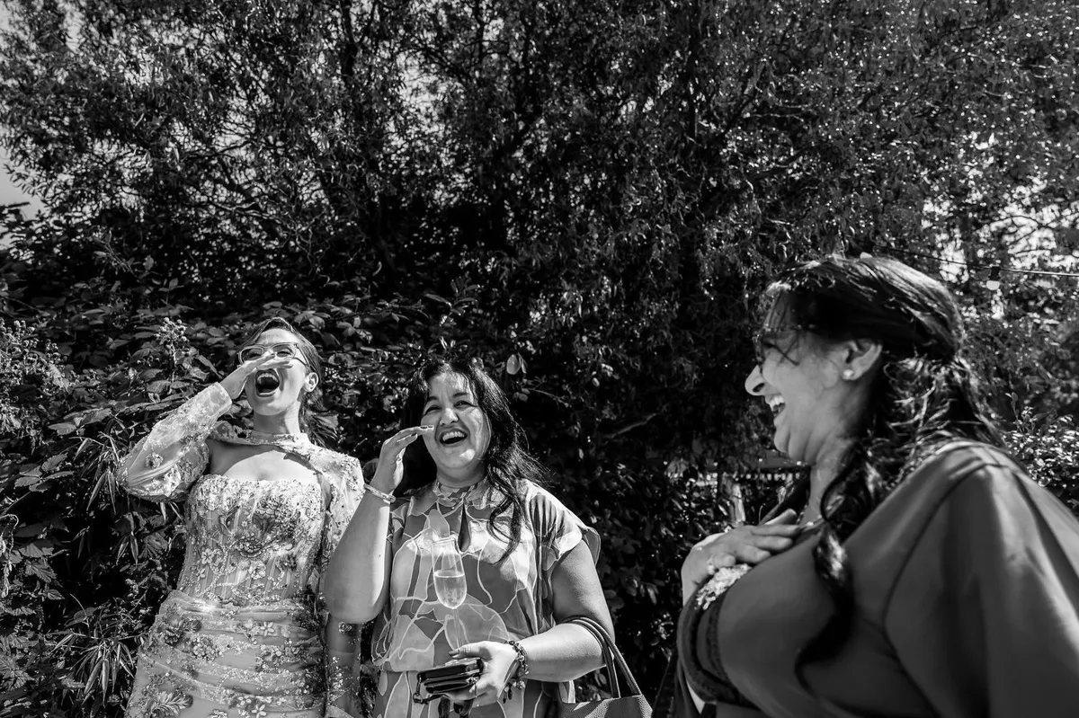 Drie gasten lachen en huilen van ontroering tijdens de ceremonie (zwart-wit)